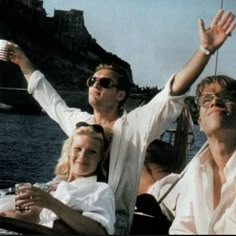 a man and two women sitting on a boat with their arms up in the air