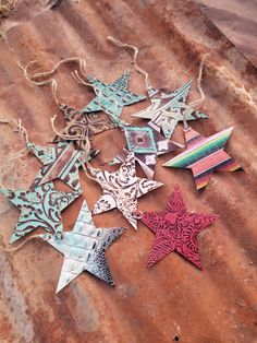 six metal stars are laying on top of a rusty piece of tin and some string