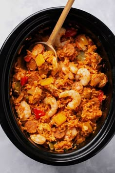 a bowl filled with rice and shrimp next to a wooden spoon