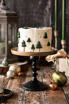 a white frosted cake sitting on top of a wooden table next to christmas decorations