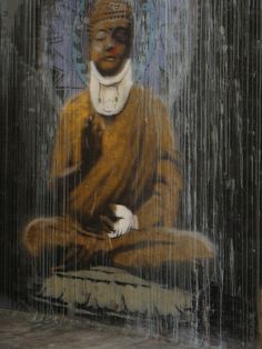 a buddha statue sitting on top of a wooden bench in front of a rain shower