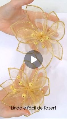 two hands are holding flowers made out of organine and gold thread, with the video below it