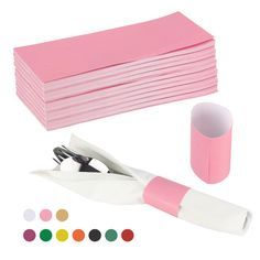 a stack of pink napkins next to a pair of scissors and a roll of colored paper