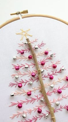 a cross stitch christmas tree with pink and silver ornaments on it's hoop frame