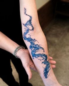 a woman's arm with blue ink on it and water running down the arm