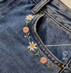 a pair of jeans with daisies on the side and buttons in the back pocket