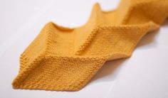 a yellow knitted tie laying on top of a white table