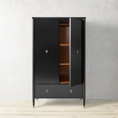 a black cabinet with two doors and shelves on the bottom, in front of a white wall