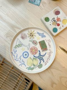 there is a plate that has pictures on it and paintbrushes next to it