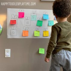 a young boy standing in front of a bulletin board with post it notes on it