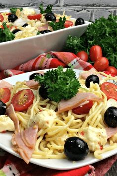 two white plates filled with pasta, meat and veggies on top of a table