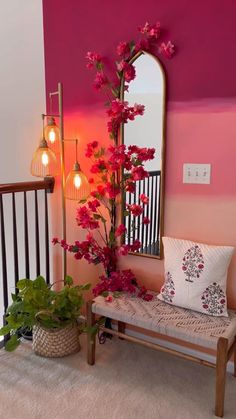 a bench sitting next to a pink wall with flowers on it and a mirror behind it