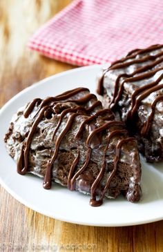 two pieces of cake on a white plate with chocolate drizzled over it