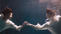 two people holding hands under the water