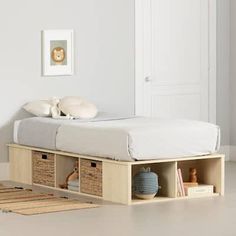 a bed with two storage bins underneath it in a room that has white walls