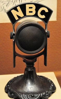 an old fashioned microphone sitting on top of a pedestal in front of a sign that says nbc