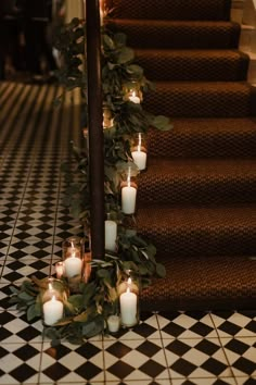 candles are lined up on the stairs with greenery