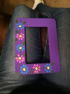 a purple frame with colorful flowers painted on it and a cat sitting in the background