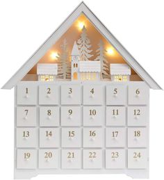 a white house shaped calendar with lights on the roof and trees in the front, against a white background