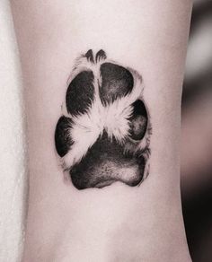 a black and white dog paw tattoo on the right side of the ankle, showing it's claws