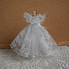 an angel doll is sitting on a lace doily