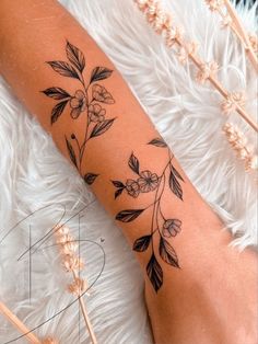 a woman's arm with flowers and leaves on it