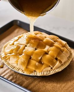 someone pouring caramel sauce on top of a pie