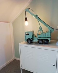 a toy crane sitting on top of a white dresser next to a lamp and wall