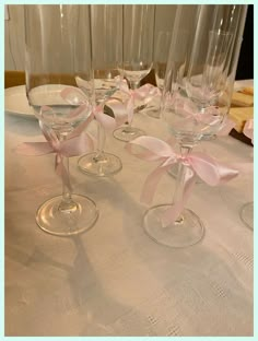 four wine glasses with pink bows are sitting on a table