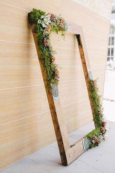 a wooden ladder decorated with greenery and succulents is leaning against a wall