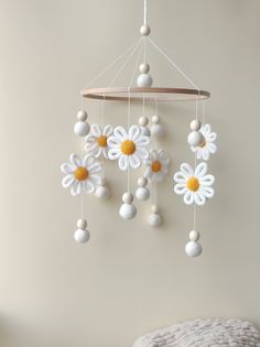 a crocheted mobile with white and yellow flowers hanging from it