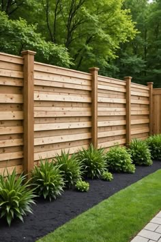 a wooden fence surrounded by lush green grass and plants on the side of a brick walkway