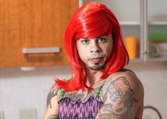 a man with red hair and tattoos standing in a kitchen