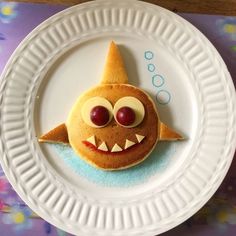 a white plate topped with a cookie shaped like a shark and two eyes on top of it