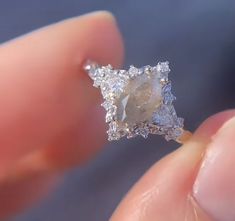 a person is holding an engagement ring with a large stone in it's middle