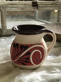 a red and white vase sitting on top of a bed