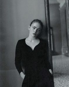 a black and white photo of a woman standing in front of a mirror with her hands on her hips