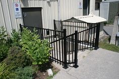 a gated entrance to a building next to some plants and bushes in front of it