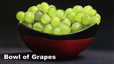 a red bowl filled with green grapes on top of a table