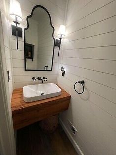 a white sink sitting under a mirror in a bathroom next to a wooden counter top