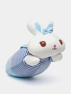 a stuffed rabbit is sitting on top of a blue and white striped pillow with a bow around its neck