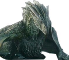 a green and black dragon statue sitting on top of a white surface with its eyes closed