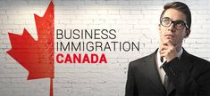 a man in a suit and tie standing next to a brick wall with the canadian flag on it