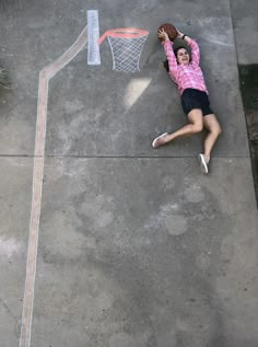 a woman laying on the ground with a basketball in her hand and net above her head