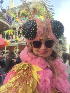 a woman in pink and gold costume with sunglasses on her head, at a carnival