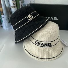 two chanel hats sitting on top of a white table next to books and magazines