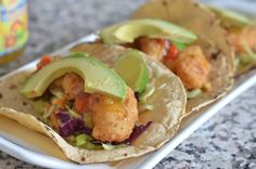 two tacos on a plate next to a can of soda