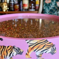 there is a large pink bowl with two tigers on the bottom and gold flakes around it