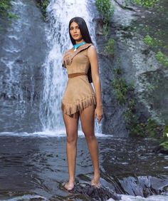 a beautiful woman standing in front of a waterfall wearing a native american style outfit with feathers on her head