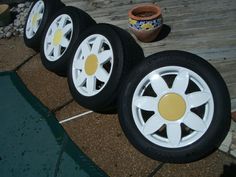 four white wheels with yellow spokes are lined up next to each other on the ground